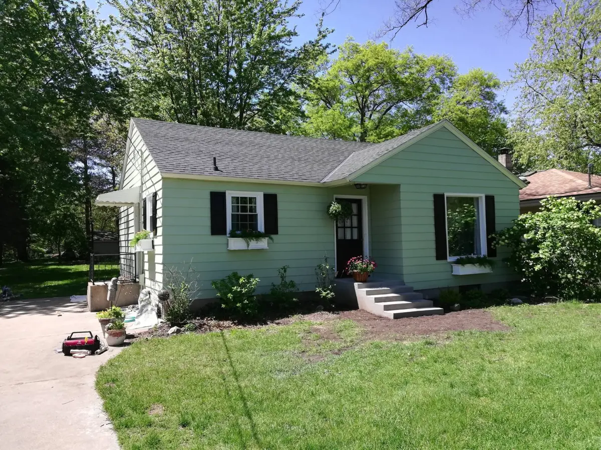 Ranch home painted light green with black shutters and white trim
